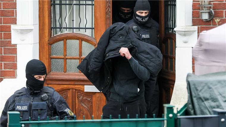 Polizei durchsucht Wohnungen von gewaltbereiten Fußballfans Polizeibeamte führen einen Tatverdächtigen aus einem durchsuchten Haus.