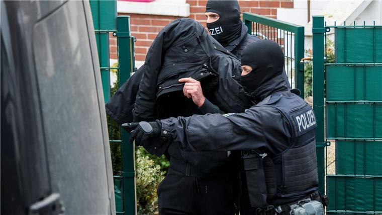 Polizei durchsucht Wohnungen von gewaltbereiten Fußballfans Polizeibeamte führen einen Tatverdächtigen aus einem durchsuchten Haus.