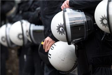 Polizisten halten während einer Demonstration ihre Schutzhelme unter dem Arm. 