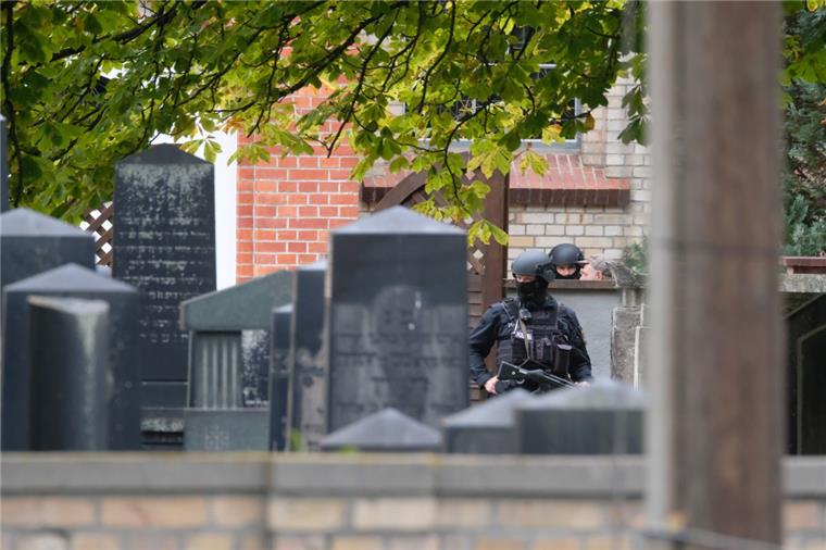Bekennervideo von Halle sahen rund 2200 Menschen Polizisten mit Schutzhelmen stehen zwischen Grabsteinen auf dem jüdischen Friedhof in Halle.