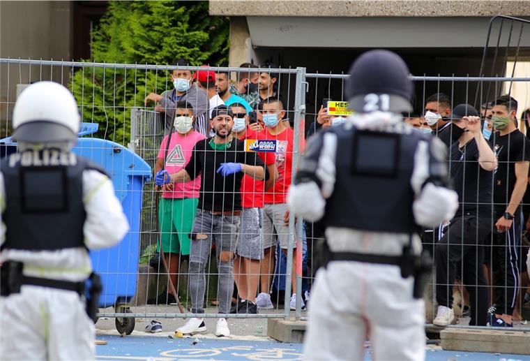 Quarantäne in Göttingen: Bewohner verletzen Polizisten Polizisten sehen sich einer Gruppe junger Männer gegenüber, die sich hinter einem Zaun versammelt hat.