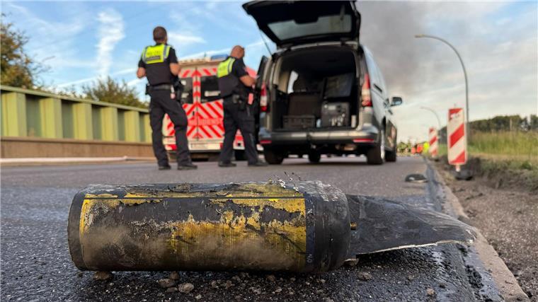 Polizisten stehen hinter einem Metallbehälter. Trümmerteile sollen bei dem Brand Hunderte Meter weit geflogen sein. 