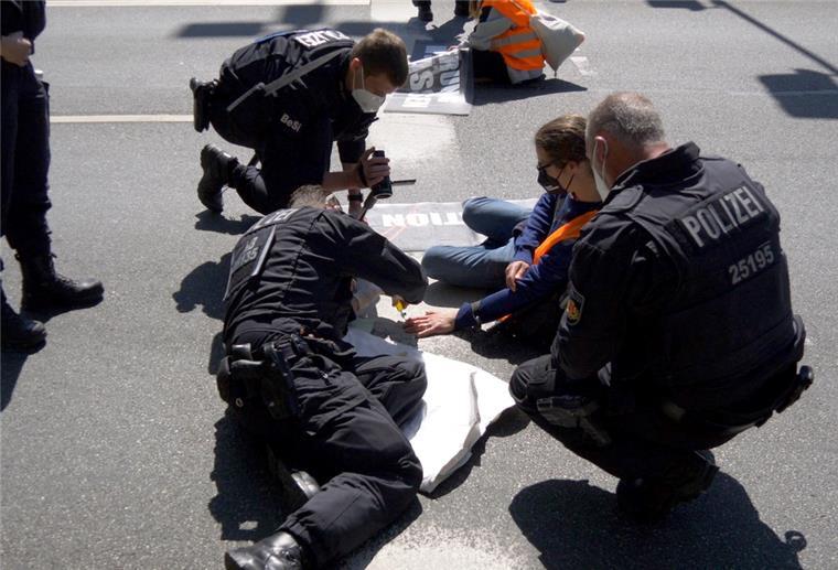 Polizisten versuchen die fest geklebten Hände von Klimaschützern vom Asphalt zu lösen, die sich an einer Autobahnabfahrt der A27 fest gemacht hatten. Die Mitglieder der Organisation Letzte Generation forderten auf Plakaten einen Ausstieg aus fossilen Energien.