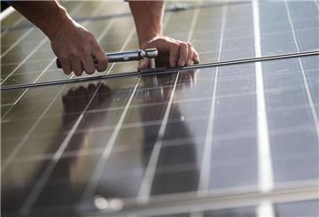  Mitarbeiter einer Firma montieren Photovoltaikmodule auf dem Dach eines Wohnhauses. 