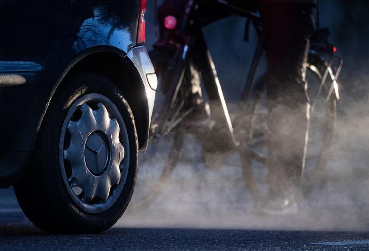 Schlechte Luft über Bremerhaven und der Region ARCHIV - 23.11.2021, Baden-Württemberg, Stuttgart: Ein Radfahrer steht neben einem Auto von Mercedes mit Dieselantrieb, dessen Abgase in der kalten Morgenluft sichtbar werden. (zu dpa: «Nur noch am Bodensee höhere Feinstaubbelastung») Foto: Marijan Murat/dpa +++ dpa-Bildfunk +++
