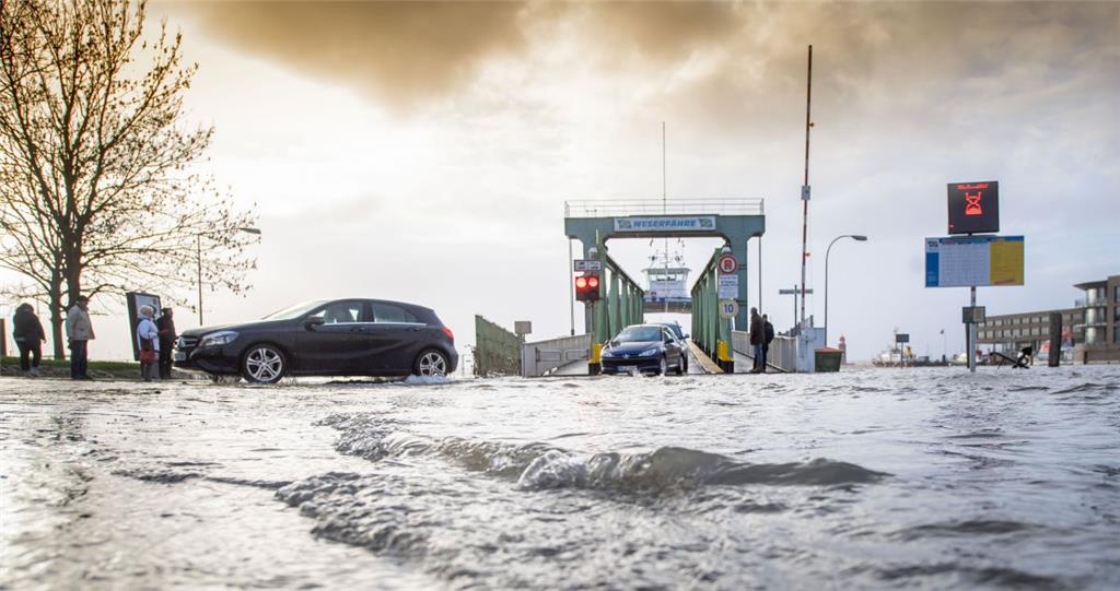 Radfahrer, Fußgänger und Autofahrer pendeln trotz Hochwasser mit der Weserfähre ...