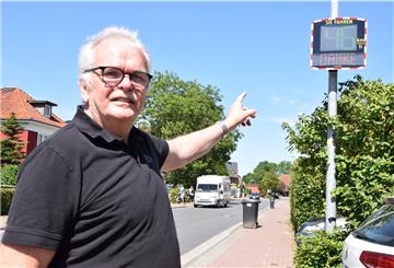 Ralph Krümpelmann zeigt auf das neue Messdisplay an der Butjadinger Straße. Er ist der Vorsitzende des Bürgervereins Nordseebad Burhave, der das Gerät angeschafft hat, um Raser auszubremsen.