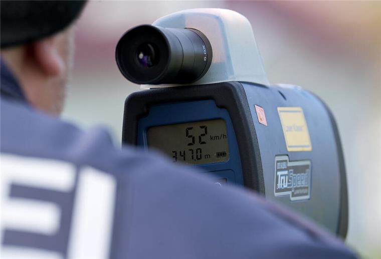Ein Polizist misst mit einem Lasermessgerät die Geschwindigkeit von Verkehrsteilnehmern. 