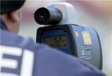 Ein Polizist misst mit einem Lasermessgerät die Geschwindigkeit von Verkehrsteilnehmern. 