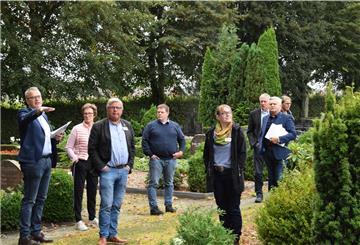 Ratsherr Olaf Wendelken (links) erläutert Mitgliedern der Bewertungskommission des Landkreises die nun laufende Umgestaltung des Friedhofes in Rhade.