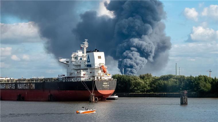 Rauch ist hinter einem Schiff zu sehen; in der Nähe des Einsatzortes fließt die Norderelbe. 
