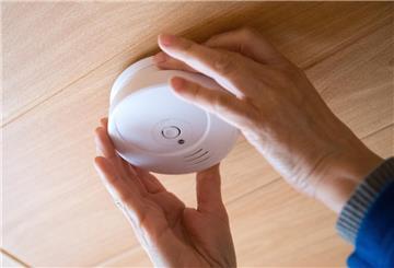 Ein Mann überprüft einen Rauchmelder an der Decke eines Zimmers. Rauchmelder mit festverbauten Akkus gelten ab August als Elektroschrott. Sie müssen auf besondere Weise entsorgt werden und gehören nicht mehr in den Restmüll.
