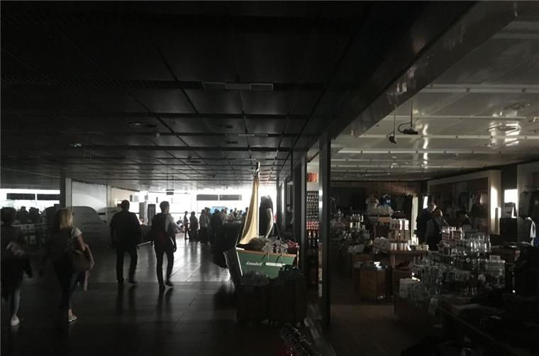 Reisende gehen während eines Stromausfalls durch den unbeleuchteten Hamburger Flughafen.

