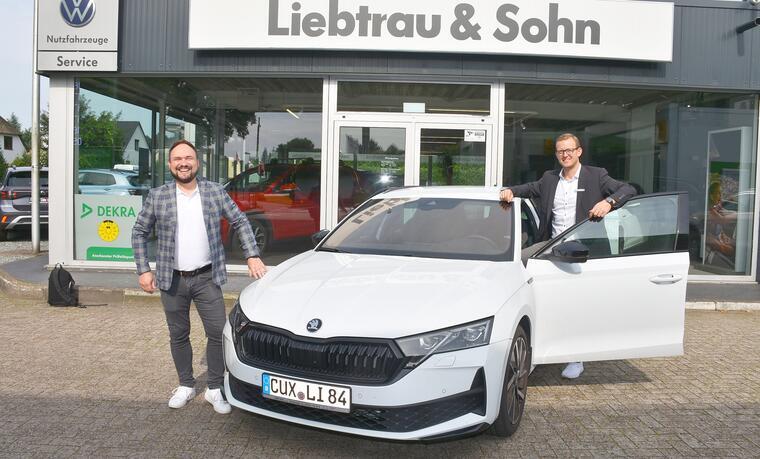 René Badenhop und René Rahden stehen an einem weißen Skoda vor ihrem Autohaus