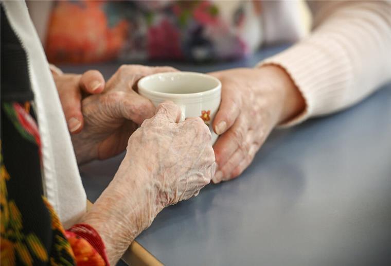 Sterbevierteljahr & Witwenrente: Das steht Hinterbliebenen zu Eine Betreuungskraft hilft einer blinden Frau mit der Kaffeetasse