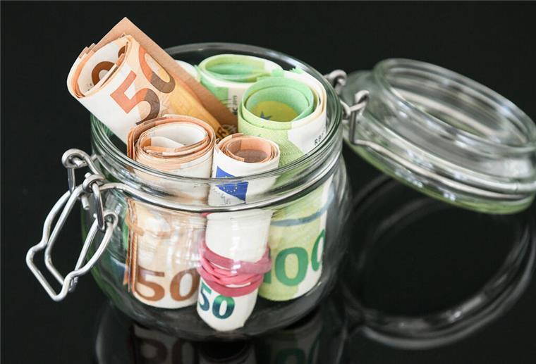 Rollen aus Fünfzig-Euro-Geldscheinen und Hundert-Euro-Geldscheinen stecken in einem Glas mit Bügelverschluss