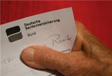Eine ältere Frau hält ihren Rentenbescheid in der Hand.