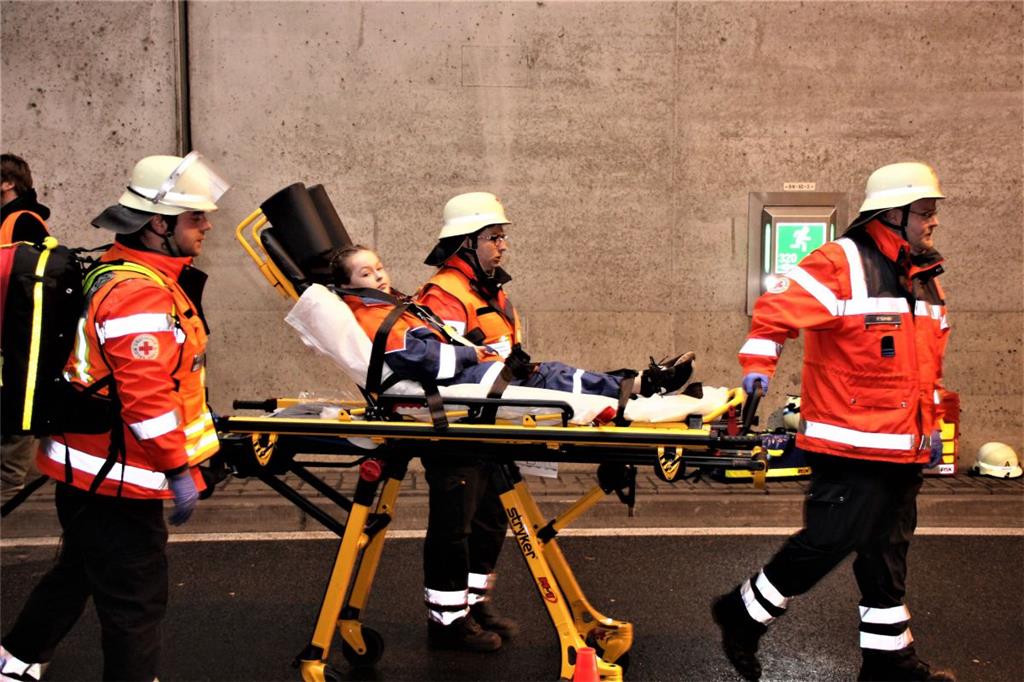 Rettungssanitäter bringen eine verletzte Person auf einer Trage zum nächsten Kra...