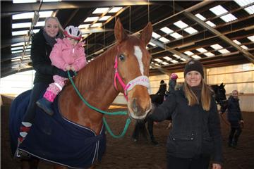Sabrina Schultze hält die dreijährige Emilia sicher fest, während Svenja Hilgen die beiden auf Fuchsstute Mira durch die Halle führt. Am Ende des aufregenden Erlebnisses traben sie sogar gemeinsam.