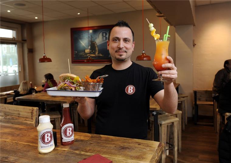 Burger aus Bremerhaven Sam Aypar ist der Betriebsleiter der Burger Bar am Theodor-Heuss-Platz. In der Hand hält er ein Hamburger-Gedeck mit Süßkartoffel-Pommes und einen der Cocktails, die die Bar ihren Besuchern anbietet.