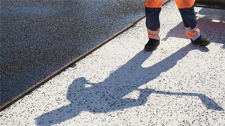 Kreisstraße 48 wird ab Montag voll gesperrt Der Schatten eines Bauarbeiters fällt auf den Boden einer Straße, die asphaltiert wird. Die Kreisstraße 48 im Landkreis Cuxhaven wird in zwei Abschnitten saniert und bleibt bis September gesperrt.