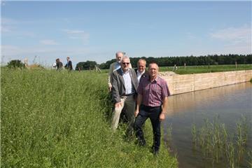 Saubere Sache: Ingenieur Hans Wilhelm Hammerich (Born & Ermel), Bürgermeister Ulf Voigts, Bauunternehmer Ralf Mehrtens und Ortsvorsteher Wilfried Geils stellen das Rückhaltebecken mit Bodenfilter vor. Im Hintergrund die Tauchwand aus Holz, die Schwimmstoffe zurückhalten soll.  