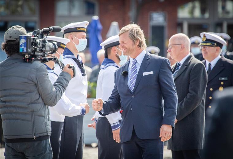 Schauspieler Henning Baum spricht zu Rekruten in Bremerhaven Schauspieler Henning Baum gratuliert – gefolgt von Bremerhavens Stadtverordnetenvorsteher Torsten von Haaren – den Marine-Rekruten und wird dabei gefilmt.