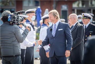 Schauspieler Henning Baum gratuliert – gefolgt von Bremerhavens Stadtverordnetenvorsteher Torsten von Haaren – den Marine-Rekruten und wird dabei gefilmt.