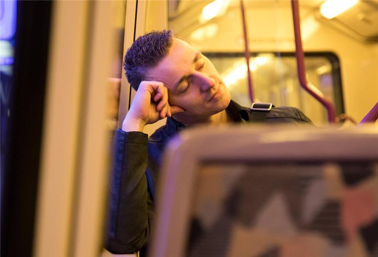 Ein Mann schläft in einer Bahn. Schichtarbeit kann heftige Folgen für den Körper haben. Wir zeigen, was das bedeutet.