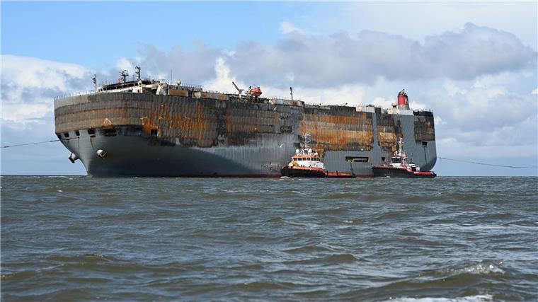 100 Tage nach Brand: „Fremantle Highway“-Zukunft ungewiss Schlepper begleiten den schwer beschädigten Autofrachter “Fremantle Highway„ in den Hafen.