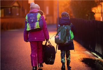 Zwei Schüler gehen am frühen Morgen auf dem Schulweg zu ihrer Grundschule in der Region Hannover. 