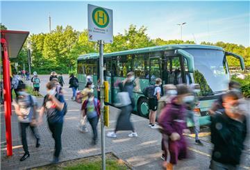 Schülerinnen und Schüler in einer verwischten Optik vor einem Schulbus am Schulzentrum in Schiffdorf. 