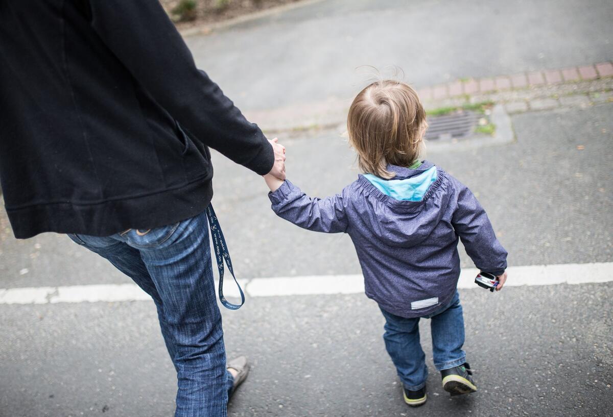 Eine Mutter hält ihren Sohn an der Hand.