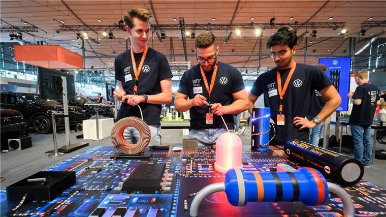 Sean (l-r), Felice und Görkem spielen bei der IdeenExpo in der Messe Hannover am Stand von VW ein Rennen mit LED-Lampen.