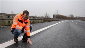 Sebastian Post, Leiter der Außenstelle der Autobahngesellschaft, hockt auf der gesperrten Fahrbahn der Autobahn 7.