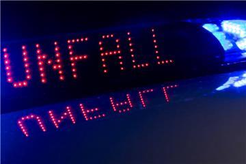 Das Blaulicht auf einem Fahrzeug der Polizei leuchtet in der Dunkelheit, während auf dem Display der Hinweis «Unfall» zu lesen ist