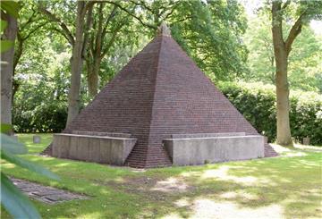 Eine Pyramide aus Klinkersteinen steht auf einer großen Rasenfläche.