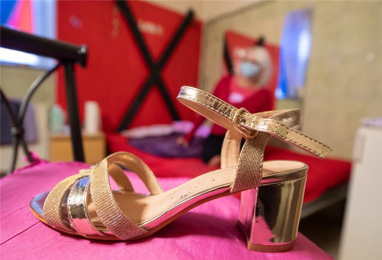 Nordenham: Bordell betrieben und Sozialhilfe kassiert Ein goldener Schuh mit Riemchen und Absatz steht auf einem pinken Stuhlpolster. Dahinter ist schemenhaft eine Frau zu erkennen.