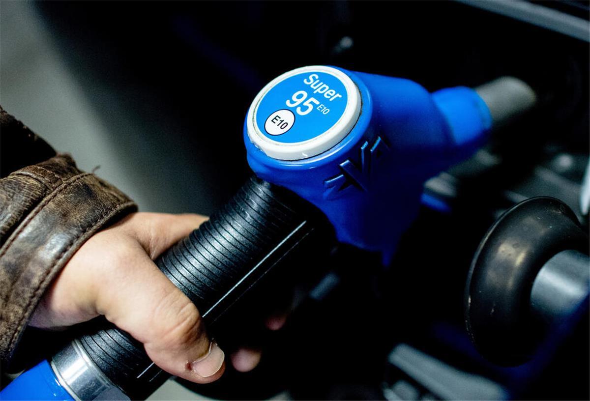 Eine Person hält einen Zapfhahn mit der Aufschrift Super E10 und betankt damit ein Auto. Um den günstigen Sprit E10 gibt es immer noch viele Vorurteile.