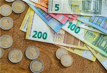 Geldschein und Geldmünzen liegen auf einem Holztisch. Seit Juli gibt es für Rentner mehr Geld. Doch sie sind nicht die einzigen die von den neuen Regeln profitieren.
