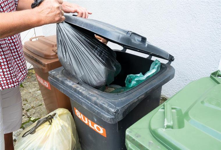Neue Müll-Regel gilt! Diese Mülltonnen werden jetzt nicht mehr geleert Ein Mann in kariertem Hemd wirft einen Müllsack in den Restmüll. Seit Mai gelten strengere Regeln: Wer seine Biotonne falsch befüllt, kann auf dem Müll sitzen bleiben. Und muss womöglich Bußgelder zahlen.