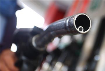 Eine Frau hält an einer Tankstelle vor einer Zapfsäule eine Zapfpistole