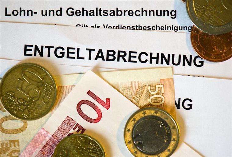 Auf Lohn- und Gehaltsabrechnungen (Entgeltabrechnungen) liegen Euromünzen und Eurogeldscheine. Der Mindestlohn legt fest, wie viel Geld jemand wenigstens bekommt für eine Stunde Arbeit.