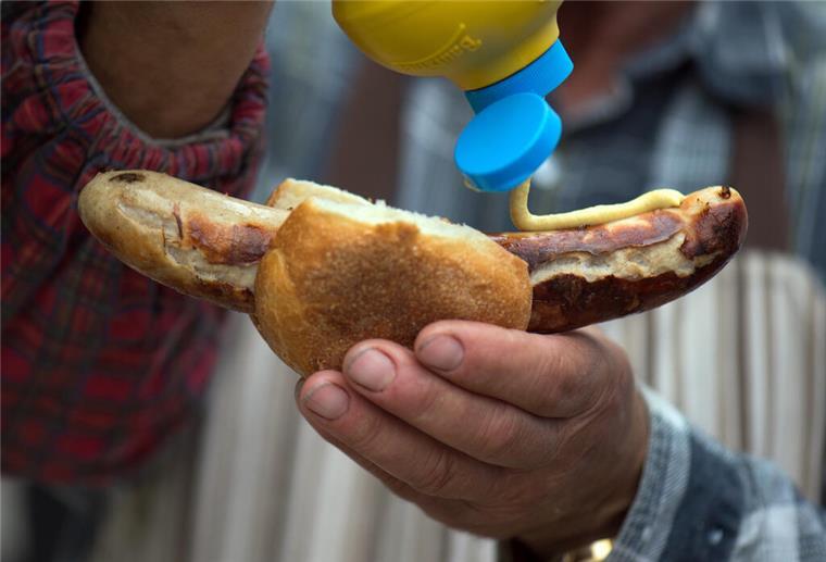 Unkrautvernichter Glyphosat ist in unserem Senf? Öko-Test deckt auf Senf auf einer Thüringer Rostbratwurst in der Hand eines Mannes.