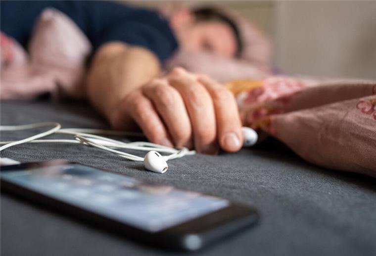 Ein Mann schläft mit einem Smartphone neben sich.