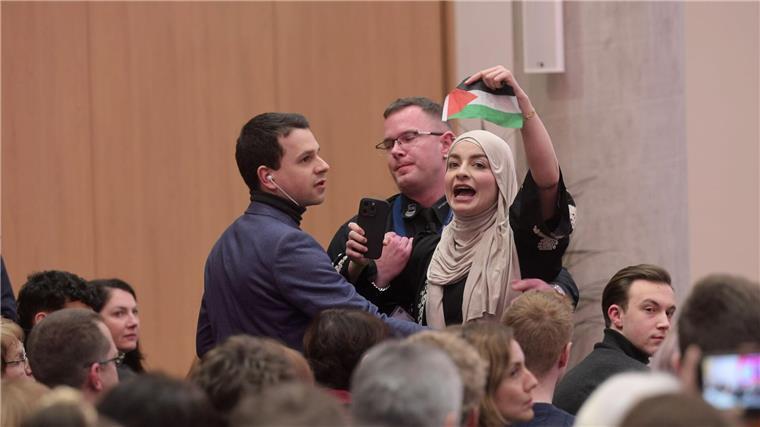 Pro-palästinensische Zuschauer stören Scholz-Veranstaltung Sicherheitskräfte führen eine pro-palästinensische Zuschauerin nach Zwischenrufen aus dem Saal.