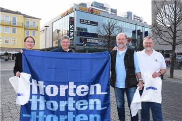 Sie laden ehemalige Horten-Beschäftigte ein (von links): Stadtarchivleiterin Dr. Julia Kahleyß, die ehemalige Betriebsrätin Christa Utech und die ehemaligen Betriebsratsvorsitzenden Achim Steyer und Karlheinz Michen mit Kaufhaus-Relikten vor ihrer früheren Wirkungsstätte, dem heutigen Hanse-Carré. 