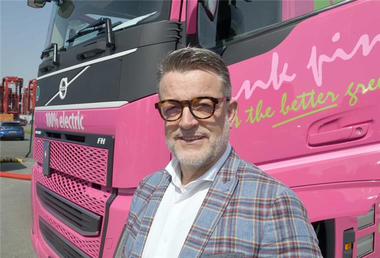 Bremerhaven: Spedition Glomb testet Elektro-Laster Mann vor einem pinkfarbenen Lastwagen