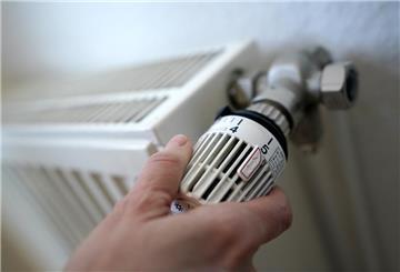 Eine Frau dreht an einem Heizungsthermostat.