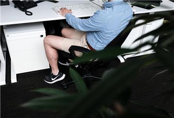 Ein Mann sitzt mit kurzer Hose an seinem Arbeitsplatz.